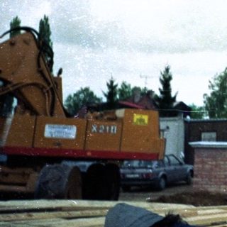 Construction worker standing on heavy machinery in rainy weather.