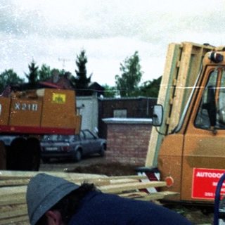 Construction worker standing on heavy machinery in rainy weather.