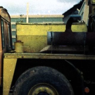 Construction worker standing on heavy machinery in rainy weather.