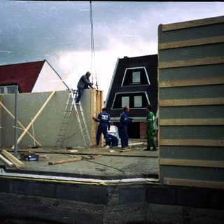 Construction workers assembling house exterior walls.