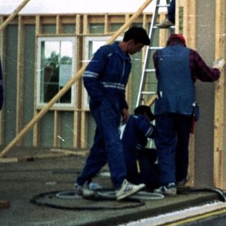 Construction workers assembling wooden house frame.