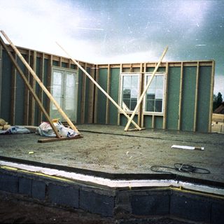 Frame-up stage of house construction with worker.