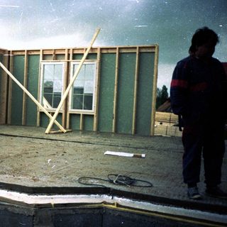 Frame-up stage of house construction with worker.