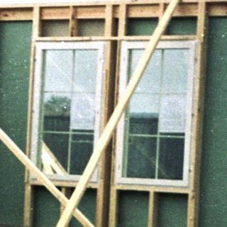 Frame-up stage of house construction with worker.