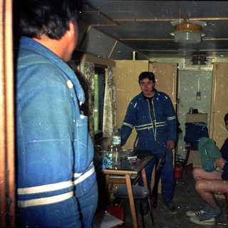 Indoor scene with three men in work uniforms.