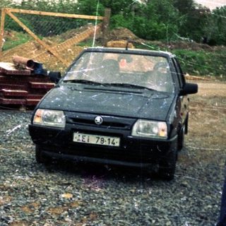 Construction site with excavator, car, and construction materials.