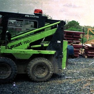 Construction site with excavator, car, and construction materials.