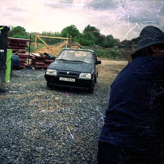 Construction site with excavator, car, and construction materials.