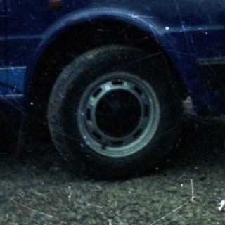 House under construction or repair, rain, blue car parked.