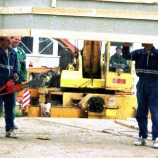 Construction crew building a two-story house frame.