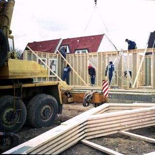 Construction workers assembling wooden house frame.