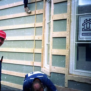 Workers installing siding on a building.