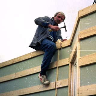 Man installing wooden framing on building exterior.