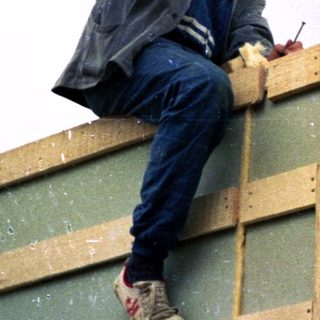 Man installing wooden framing on building exterior.