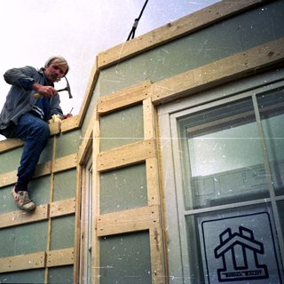 Man installing wooden framing on building exterior.