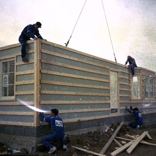 Construction workers assembling modular house sections.
