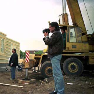 Construction site with modular home being lifted by crane.
