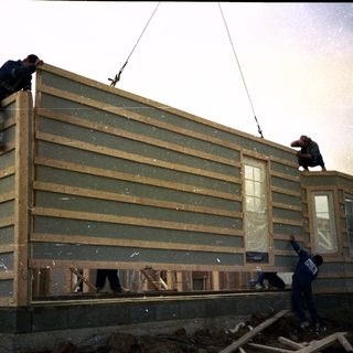 Construction workers installing exterior siding on a house.