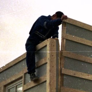 Construction workers installing exterior siding on a house.