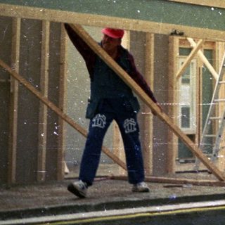 Construction workers installing exterior siding on a house frame.