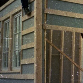 Construction workers installing exterior siding on a house frame.