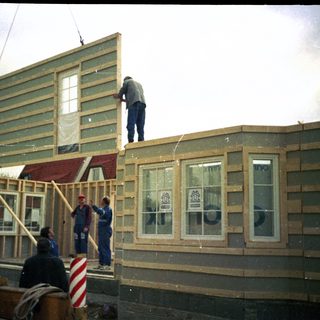 Construction workers assembling wooden house frame.