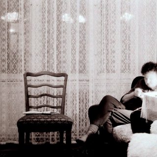 Child reading on bed near window.