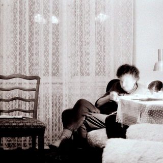 Child reading on bed near window.
