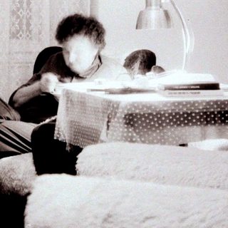Child reading on bed near window.