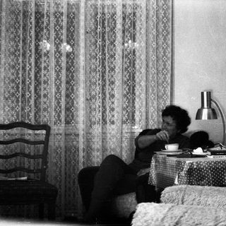 Person sitting on bed drinking tea.