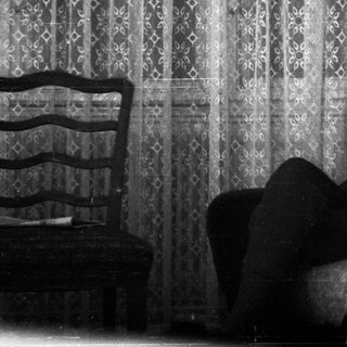 Person sitting on bed drinking tea.