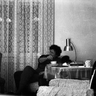 Person sitting on bed drinking tea.