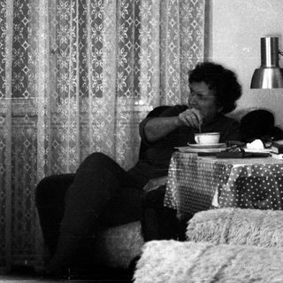 Person sitting on bed drinking tea.