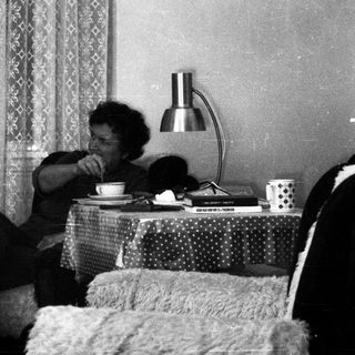 Person sitting on bed drinking tea.