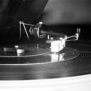 Vinyl record on turntable with tonearm lowered.