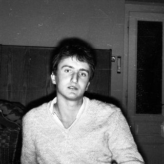 Young man indoors, looking surprised.