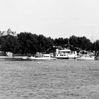 Historic waterfront cityscape with boats and mosque.