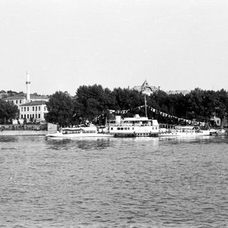Historic waterfront scene with boats and city buildings.