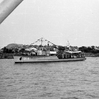 Military patrol boats in harbor near coastal town.