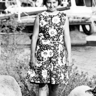 Girl standing with herd of sheep outdoors.