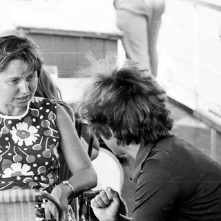 Two people conversing outdoors near a boat.