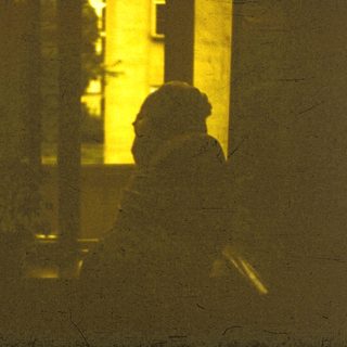 Silhouette of person standing near building at night.