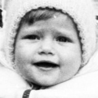 Baby in vintage carriage on rural road.
