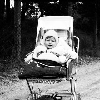 Baby in vintage carriage on rural road.