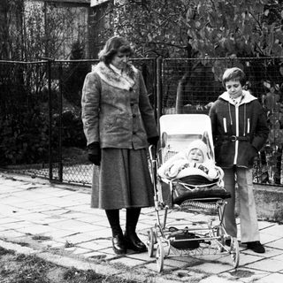 Family with baby stroller outdoors in residential area.
