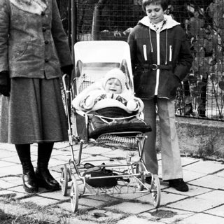 Family with baby stroller outdoors in residential area.