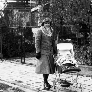 A woman pushing a baby stroller outdoors.