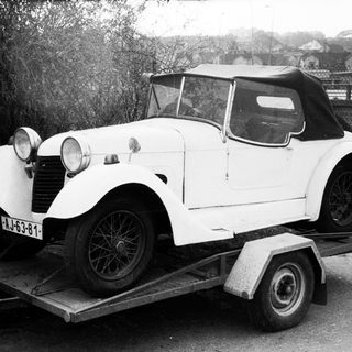 Vintage white convertible car on trailer.
