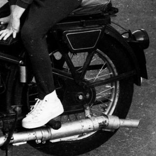 A woman and child pose on a vintage motorcycle.