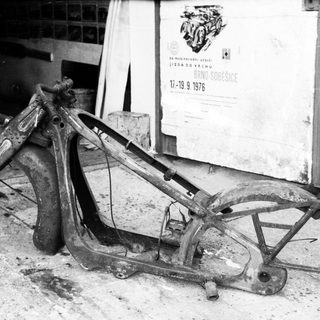 Destroyed motorcycle frame on workshop floor.